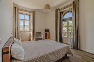 a bedroom with a bed and a large window at Quinta Calheiros - Rural Place in Coucieiro