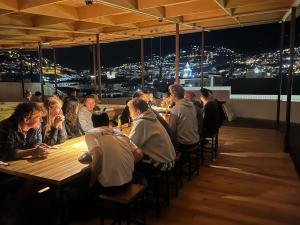 um grupo de pessoas sentadas em mesas em um restaurante à noite em Community Hostel Quito em Quito