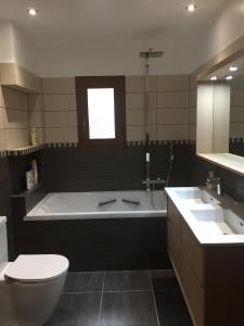 a bathroom with a tub and a toilet and a sink at Chalet Maillet Mieussy in Mieussy