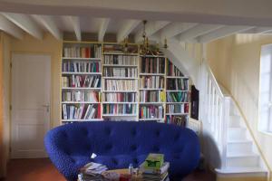 sala de estar con sofá azul y estantería con libros en Maison entière avec piscine chauffée 4p, en Brétigny