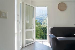 un salon avec un canapé et une porte coulissante en verre dans l'établissement La Maison Paradiso - vista panoramica & giardino, à Alpette 20 autres photos
