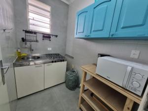 eine Küche mit einer Spüle, einem Herd und blauen Schränken in der Unterkunft Apart Grécia l Aconchego nas Montanhas l Águas de Lindóia in Águas de Lindóia