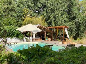 a swimming pool with an umbrella and a gazebo at La Réserve Taïno in Arjuzanx