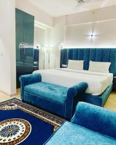 a bedroom with a bed and two blue chairs at Neel Skye - Couple Friendly - DLF My Pad, Gomtinagar , Lucknow in Lucknow