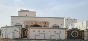 ein weißes Gebäude mit einem Tor davor in der Unterkunft Mountain Balcony House in Nizwa