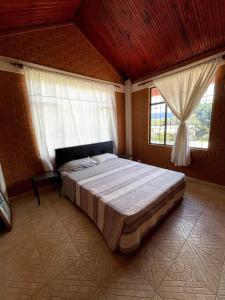1 dormitorio con 1 cama grande y 2 ventanas en Hermosa y lujosa cabaña familiar, en Chachagüí