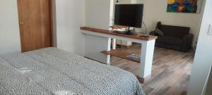 a bedroom with a bed and a desk with a television at Pequeña casa en chacras de coria in Chacras de Coria