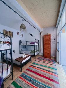 a bedroom with two bunk beds and a rug at Sunrise Hostel Taghazout in Taghazout