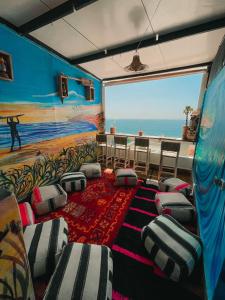 タガズートにあるSunrise Hostel Taghazoutの椅子とビーチの絵画が飾られた部屋