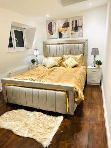 Luxury Morden 4 bedroom Flats which will make you unforgettable في لندن: سرير كبير بملاءات ومخدات ذهبية في غرفة النوم