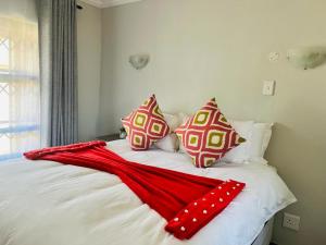 ein Bett mit einer roten Decke und Kissen darauf in der Unterkunft Hillas Ridge Guesthouse in Vanderbijlpark