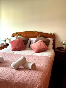 Una cama con almohadas rosas y blancas. en El rincón soleado, en Medina de Pomar