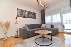 a living room with a gray couch and a table at Apartman Dina in Pirot