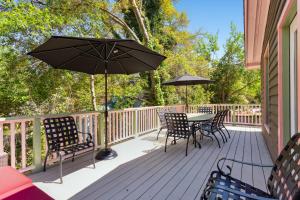 a deck with a table and chairs and an umbrella at Folly Vacation Vintage Cottage 317 East in Folly Beach