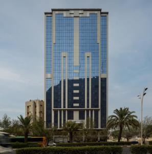 a tall glass building with palm trees in front of it at Snood Al Maaly Hotel in Mecca