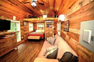 uma cabina de madeira com um sofá e uma televisão em The Americana - Parker Creek Bend Cabins em Murfreesboro