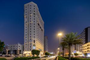 a tall white building in a city at night at Snood Al Dana Hotel in Makkah