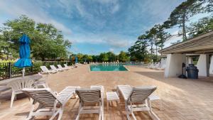 a group of chairs and a swimming pool with blue umbrellas at Tall Pines Villa River Club Golf Views in Pawleys Island