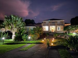 een groot huis met palmbomen en 's nachts verlichting bij Hotel La Ponsa Itatiaia in Itatiaia