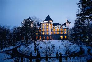 un gran edificio con luces encendidas en la nieve en Wildflower Hall, An Oberoi Resort, Shimla en Shimla