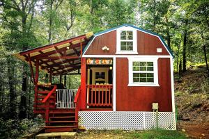 uma casa de jogos vermelha e branca com um alpendre em The Americana - Parker Creek Bend Cabins em Murfreesboro