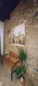 un banc en bois contre un mur de briques avec une photo dans l'établissement DIMORA AL SARACENO, à Ferrare