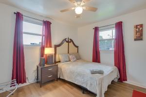 1 dormitorio con 1 cama con cortinas rojas y ventilador en Capitol Heights Home about 6 Mi to National Mall!, en Capitol Heights