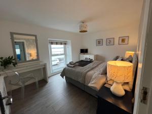 een slaapkamer met een bed en een tafel met een lamp bij Harbour View on the Lough Edge with Hot Tub in Portaferry
