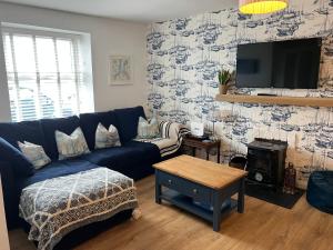 a living room with a blue couch and a tv at Harbour View on the Lough Edge with Hot Tub in Portaferry