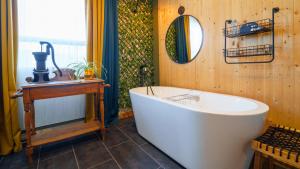 y baño con bañera blanca y espejo. en Le Refuge du Repaire, en Saint-Alexis-des-Monts