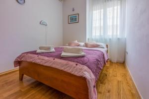 a bedroom with a large bed with a purple blanket at Room Laura in Crikvenica