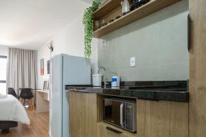 a kitchen with a microwave and a refrigerator at Maravilhoso e elegante studio para casal PGO412 in Poços de Caldas