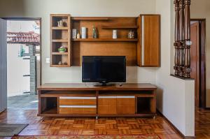 TV en un centro de entretenimiento de madera en una habitación en Chamosa e aconchegante casa em Petrópolis VGL041, en Petrópolis