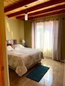 a bedroom with a bed and a window and a rug at Entre Rieles Cabañas y Restaurante in Calama