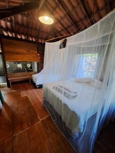 ein Schlafzimmer mit einem Himmelbett und einem Fenster in der Unterkunft Chalé com privacidade em Imbassai in Mata de Sao Joao