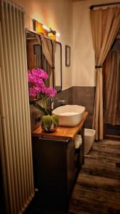 ein Badezimmer mit einem Waschbecken und rosa Blumen auf der Theke in der Unterkunft Casa22 in Abbadia San Salvatore