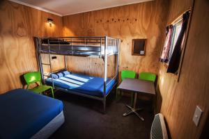 Cette chambre comprend des lits superposés, une table et des chaises. dans l'établissement Hampshire Holiday Parks - Wanaka, à Wanaka