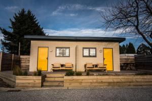 a small house with yellow doors and two benches at Hampshire Holiday Parks - Wanaka in Wanaka