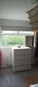 a room with a window and a dresser in front at Rockrose Stay in Cardiff