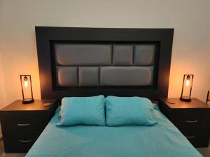 Un dormitorio con una cama azul con dos luces. en Bonito Departamento en Americana en Guadalajara