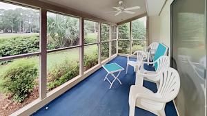a screened porch with chairs and tables and windows at Scenic Golf Villa River Club 2BR Getaway in Pawleys Island