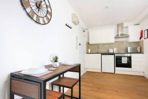 a kitchen with a table and a clock on the wall at Central Buckingham Apartment #3 with Free Parking, Pool Table, Fast Wifi and Smart TV with Netflix by Yoko Property in Buckingham