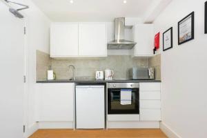 a white kitchen with white cabinets and a sink at Central Buckingham Apartment #3 with Free Parking, Pool Table, Fast Wifi and Smart TV with Netflix by Yoko Property in Buckingham