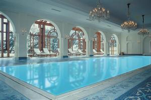 una piscina en una habitación con sillas y ventanas en Wildflower Hall, An Oberoi Resort, Shimla en Shimla