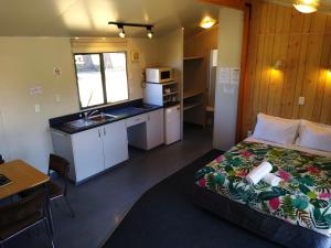 a bedroom with a bed and a kitchen with a sink at Hampshire Holiday Parks - Wanaka in Wanaka