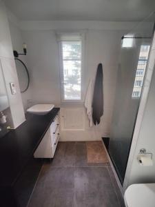 baño blanco con lavabo y ventana en Appartement cosy 40m2 - Montmartre, en París