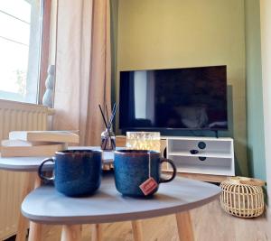 two blue coffee mugs on a table in a living room at Le murmure des Lucioles in Hamoir