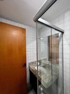 uma casa de banho com um lavatório e uma porta de vidro em Flat em Aguas Claras - Brasília - MADB1005 em Águas Claras