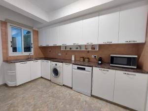 a kitchen with white cabinets and a washer and dryer at Villa Agios Georgios with Private Pool in Peyia