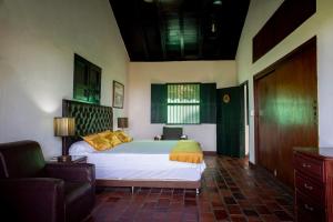 a bedroom with a bed and a couch and a chair at Sotovocce Casa Campestre in Turbaco